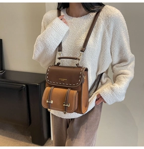 Close-up of vintage brown color-block backpack featuring white stitching and gold logo