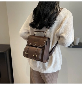 Detail of vintage brown backpack with white stitching and adjustable straps on model