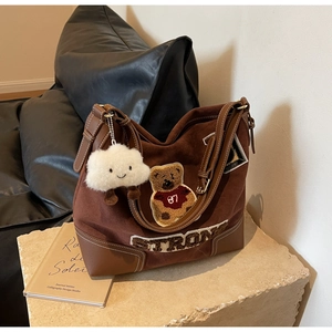 Detail of dark brown suede tote bag with teddy bear patch and white fuzzy cloud pendant