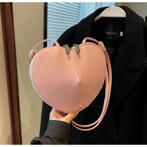Dettaglio di una borsa a tracolla rosa a forma di cuore con doppia cerniera e finitura liscia
