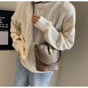 Detail view of brown vintage bucket bag with golden twist lock and leather handle