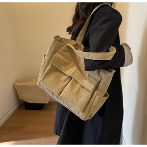 Detail view of khaki corduroy tote bag with dual front flap pockets and silver metal snaps
