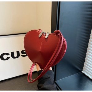 Dettaglio ravvicinato di una borsa a tracolla rossa a forma di cuore in finta pelle liscia