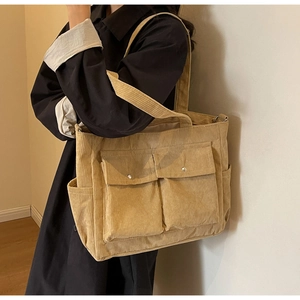Detail of beige corduroy tote bag showing front flap pockets and soft ribbed texture