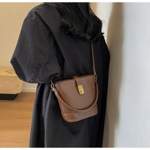 Model wearing dark brown vintage bucket bag with adjustable strap and golden lock