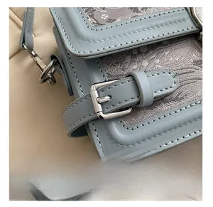 Détail de la boucle métallique argentée et de la dentelle sur le petit sac à bandoulière bleu