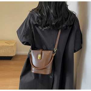 Detail view of dark brown leather bucket bag with gold metal buckle and fine stitching