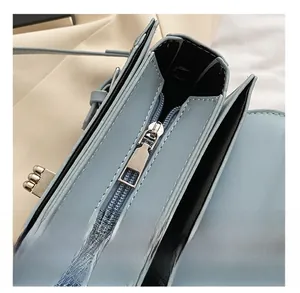Détail de la fermeture éclair en métal lisse et ferrures dorées sur le sac bleu clair
