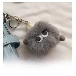 Vue détaillée du charm de sac en peluche grise avec des yeux sur un sac bleu clair