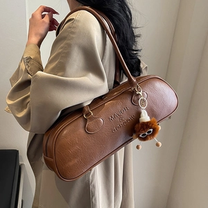 Brown vintage leather bowling shoulder bag with plush charm and embossed brand logo