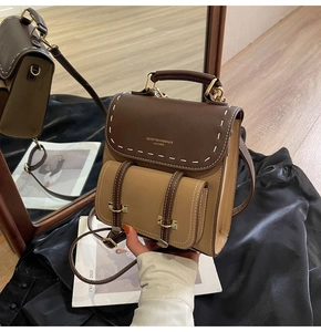 Detailed view of two-tone leather mini backpack with contrast stitching and metal buckles