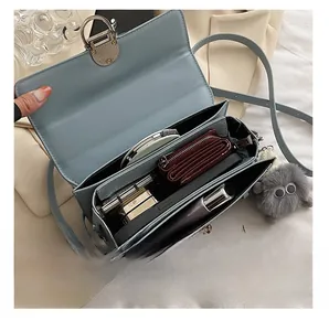 Détail intérieur d'un sac bandoulière bleu clair avec trois compartiments et fermoir métal