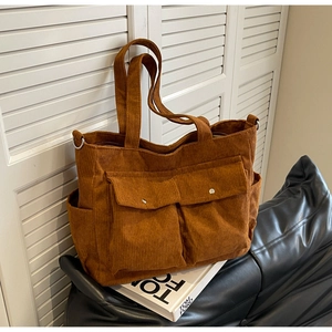 Detailed view of brown corduroy tote bag with double flip pockets and metallic buckles