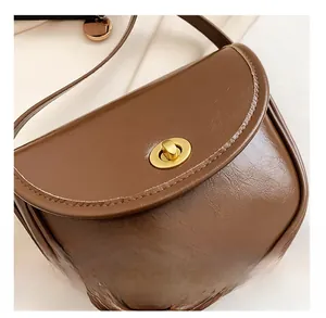 Detail shot of the vintage dark brown leather saddle bag featuring a gold twist lock closure