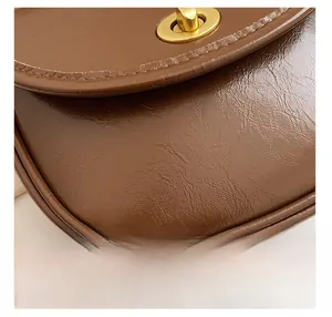 Detailed close-up of retro brown oil wax leather saddle bag with golden metal twist lock
