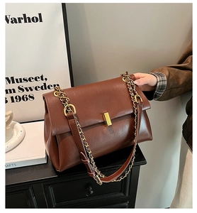 Détail du sac cabas en cuir marron vintage avec une élégante bandoulière en chaîne dorée