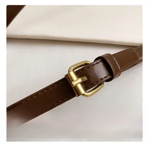 Macro detail of coffee brown leather strap with vintage gold metal buckle and stitching