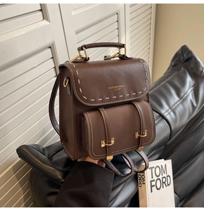 Detail of dark brown leather bag showing premium white stitching and gold metal hardware