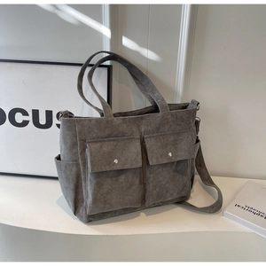 Close-up of a grey corduroy tote bag with large front pockets and adjustable strap