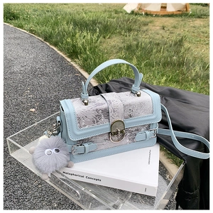 Vue détaillée du sac à main bleu clair avec motif vintage et breloque en peluche monstre