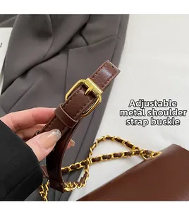 Détail de la boucle dorée réglable et de la chaîne sur un grand sac cabas marron