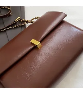 Détail du sac cabas marron montrant le fermoir doré et la bandoulière en chaîne