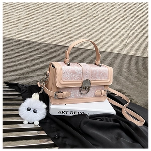 Détail d'un sac carré rose avec tissu jacquard, boucle en métal et breloque peluche