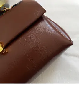 Gros plan sur la texture du cuir PU marron avec boucle en métal doré et bandoulière chaîne