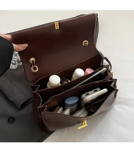 Vue de dessus montrant l'intérieur spacieux multicouche d'un sac cabas marron en cuir et boucle dorée