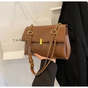 Détail du sac cabas en cuir marron foncé avec chaîne dorée et fermoir en métal élégant