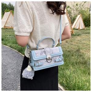 Détail du sac bandoulière bleu clair brodé avec motifs vintage et breloque en peluche