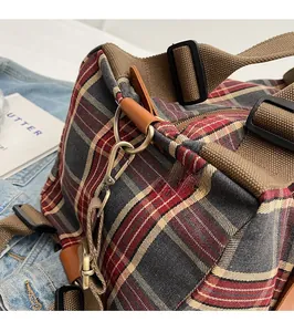 Close-up of durable bronze metal hooks and brown leather trim on vintage plaid canvas bag
