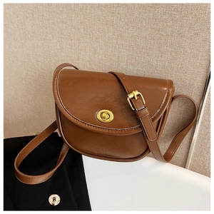 Detail of brown vintage saddle bag showing textured faux leather and gold twist-lock closure