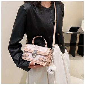 Détail du sac bandoulière rose gaufré avec boucle métallique et porte-clés peluche