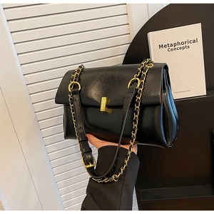Vue latérale d'un sac cabas en cuir noir brillant avec boucle dorée et bandoulière