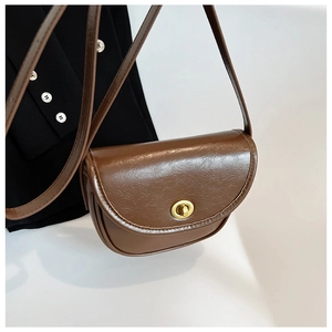 Close-up of brown faux leather saddle bag with golden metal swivel lock and pebble texture