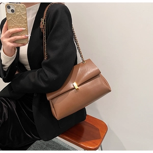 Détail de la texture en similicuir marron et du fermoir doré sur un sac à bandoulière