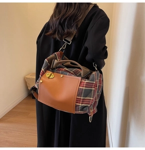 Detail of checkered crossbody travel bag with golden twist-lock closure and dual straps