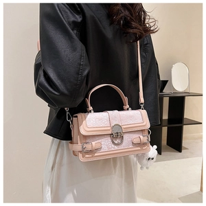 Détail d'un sac bandoulière rose clair avec gaufrage floral et pendentif hibou sur mannequin