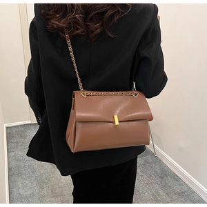 Gros plan d'un sac cabas en cuir marron avec boucle dorée et bandoulière chaîne