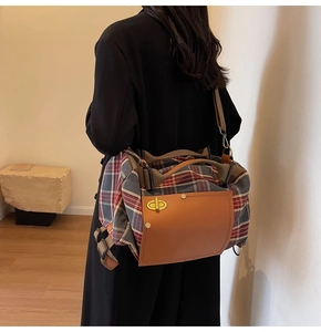 Close-up of vintage plaid travel bag with leather trim and gold twist-lock on a model