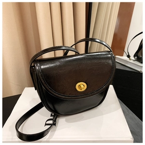 Detail view of a vintage black PU leather saddle bag featuring a retro gold twist lock closure