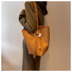 Detail of a brown lychee pattern leather tote bag worn on a shoulder for daily commute