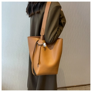 Detail of tan lychee grain leather bucket bag with wide shoulder strap on green dress