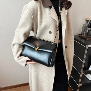 Sac fourre-tout classique en cuir noir avec chaîne dorée porté par un mannequin élégant