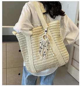 Détail d'un sac cabas en paille tissée avec pompon œil bleu et anneau en bois