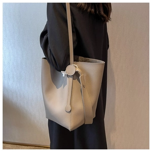 Detailed view of grey-beige lychee grain leather bucket bag with textured strap