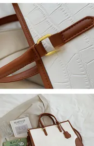 Detail of white crocodile embossed leather tote with brown trim and gold hardware