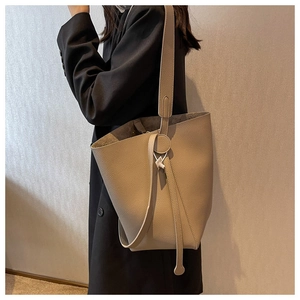 Detail of khaki bucket bag with lychee leather texture and elegant drawstring closure