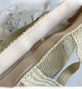 Détail de la fermeture éclair dorée et doublure en satin du sac cabas tressé beige